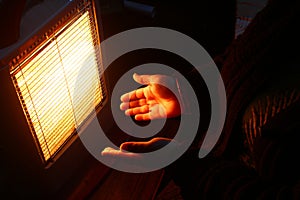 Woman hands in front of an electric room heater
