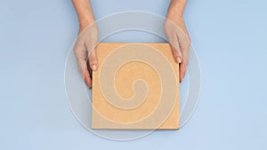 Woman hands give and another person receive brown parcel cardboard box on light blue background. Present, online