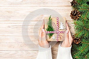 Woman hands give wrapped christmas handmade present in paper with christmas decoration. Present box on holiday on dark