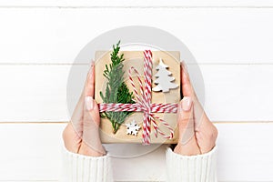 Woman hands give wrapped christmas handmade present in paper with christmas decoration. Present box on holiday on dark