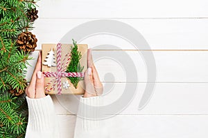 Woman hands give wrapped christmas handmade present in paper with christmas decoration. Present box on holiday on dark