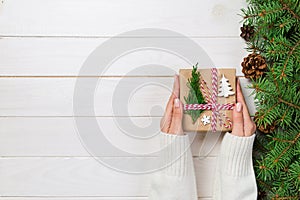 Woman hands give wrapped christmas handmade present in paper with christmas decoration. Present box on holiday on dark wooden tabl