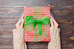 Woman hands give wrapped christmas or other holiday handmade present in colored paper . Present box, decoration of gift on dark