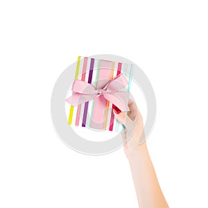 Woman hands give wrapped Christmas or other holiday handmade present in colored paper with pink ribbon. Isolated on white