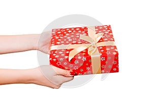 Woman hands give wrapped Christmas or other holiday handmade present in red paper with Gold ribbon. Isolated on white background,