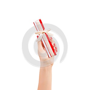 Woman hands give wrapped Christmas or other holiday handmade present in red paper with gold ribbon. Isolated on white background,