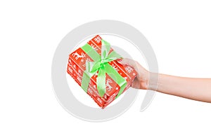 Woman hands give wrapped Christmas or other holiday handmade present in red paper with green ribbon. Isolated on white background