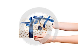Woman hands give wrapped group of Christmas or other holiday handmade present in gold paper with blue ribbon. Isolated on white