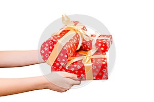 Woman hands give wrapped set of Christmas or other holiday handmade present in red paper with Gold ribbon. Isolated on white