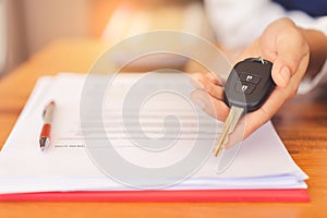 Woman hands giving a car remote key after signed contract agreement and successful deal.