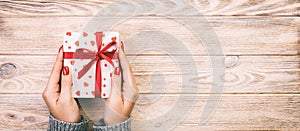 Woman hands giving Holidays gift box on wood table, Present box, red heart decoration of gift on wooden table, top view with copy