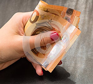 Woman hands giving money like a bribe or tips. Holding EURO banknotes on a blurred background, EU currency