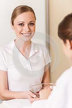 Woman hands in glass bowl with water on white towel.