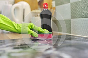 Woman hands in gloves cleans kitchen electric ceramic hob