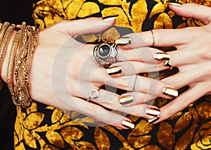 Woman hands with golden manicure lot of jewelry on fancy dress close up beauty concept