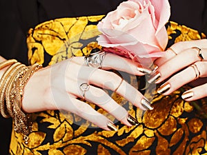 Woman hands with golden manicure lot of jewelry on fancy dress close up beauty concept