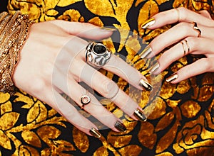 Woman hands with golden manicure lot of jewelry on fancy dress close up beauty concept