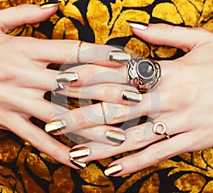 Woman hands with golden manicure lot of jewelry on fancy dress closeup beauty concept