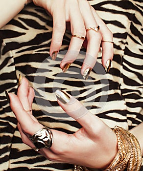 Woman hands with golden manicure lot of jewelry on fancy dress closeup beauty concept