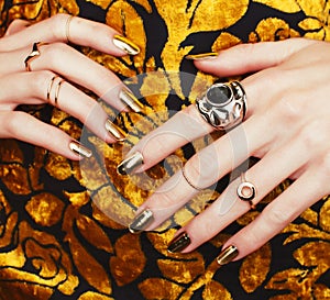 Woman hands with golden manicure lot of jewelry on fancy dress closeup beauty concept