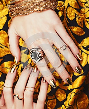 Woman hands with golden manicure lot of jewelry on fancy dress closeup beauty concept