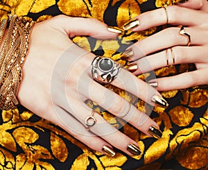 Woman hands with golden manicure lot of jewelry on fancy dress close up beauty concept photo
