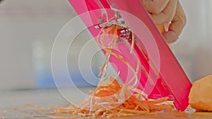 woman hands grates carrots on red grate at kitchen table