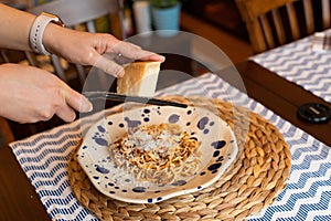 Woman hands grating parmesan cheese to homemade spaghetti bolognese