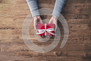 Una mujer manos en gris un suéter sobre el madera mesa dar regalo de navidad cabina lleno blanco cinta 