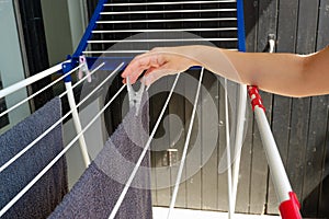Woman hands hanging her laundry on balcony on the drying rack. Female Hanging Clothes On Clothes Line Outdoors