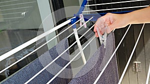 Woman hands hanging her laundry on balcony on the drying rack. Female Hanging Clothes On Clothes Line Outdoors