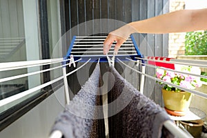 Woman hands hanging her laundry on balcony on the drying rack. Female Hanging Clothes On Clothes Line Outdoors