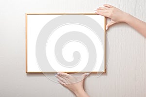 Woman hands hanging a photo frame mockup on a white wall