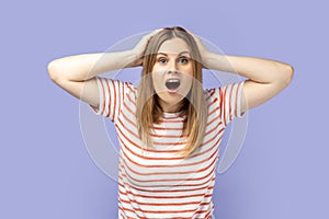 Woman with hands on head, expressing astonishment, keeping mouth widely open.