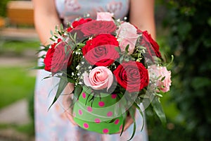 Woman hands hold box with flower bouquet of red and pink roses o