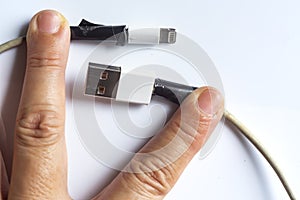 Woman hands hold Damaged white usb cable plug and micro usb plug or Old Smart Phone Charger Cable broken on white acrylic