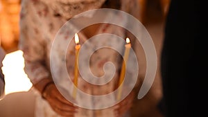 Woman hands hold lighted candles in the church