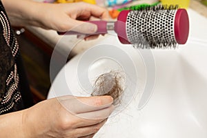 Woman hands hold lost hair and comb