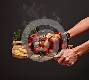Woman hands hold plate with cooked thanksgiving turkey or chicken for christmas dinner evening with steam smoke on wooden  plate