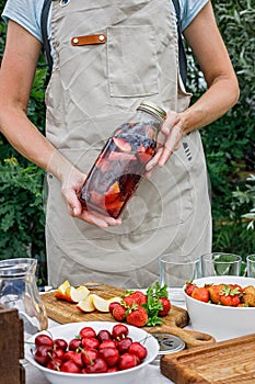 Woman hands hold a refreshing homemade lemonade or sangria punch with citrus fruits and organic berries. Summer cocktail