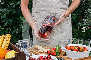 Woman hands hold a refreshing homemade lemonade or sangria punch with citrus fruits and organic berries. Summer cocktail