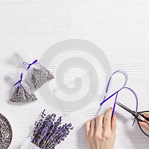 Woman hands hold scissor, make DIY lavender sachets for home, natural scented bags from organza with violet ribbon on