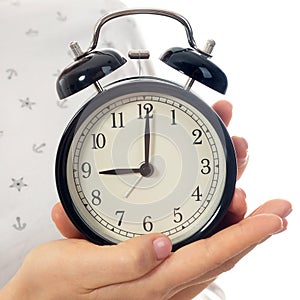 Woman hands holding black alarm clock