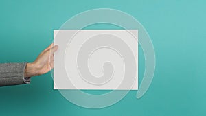 Woman hands holding blank paper and wear grey suit isolated on blue and green background