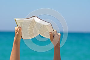 Una mujer manos posesión un libro a lectura sobre el el mar 