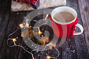 Woman hands holding Christmas coffee or tea red mug with steam, homemade gingerbread christmas cookies on a wooden table, sweeters