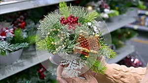 Woman hands holding Christmas decoration, fir tree branches with berries in pot