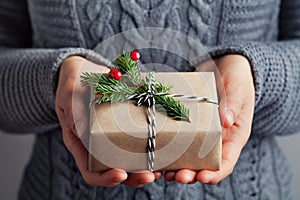 Woman hands holding christmas gift or present box decorated fir tree. Cozy winter shot.