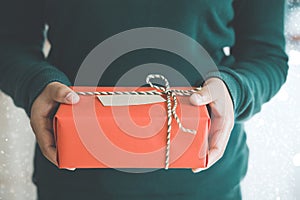 Woman hands holding Christmas handmade gift box or new year present with snow background.