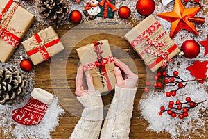 Woman hands holding Christmas present. Wooden background